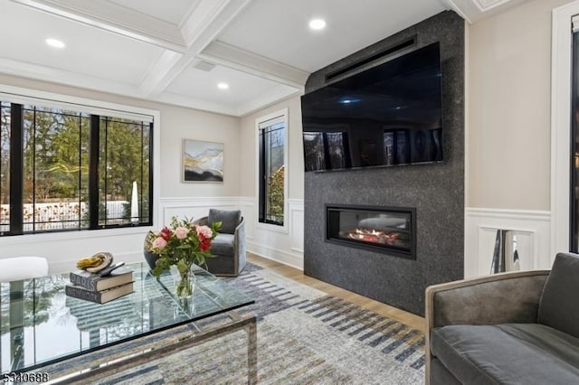 living room featuring beam ceiling, a wainscoted wall, a fireplace, wood finished floors, and coffered ceiling