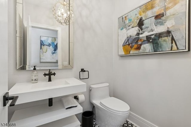 bathroom featuring a chandelier, baseboards, and toilet