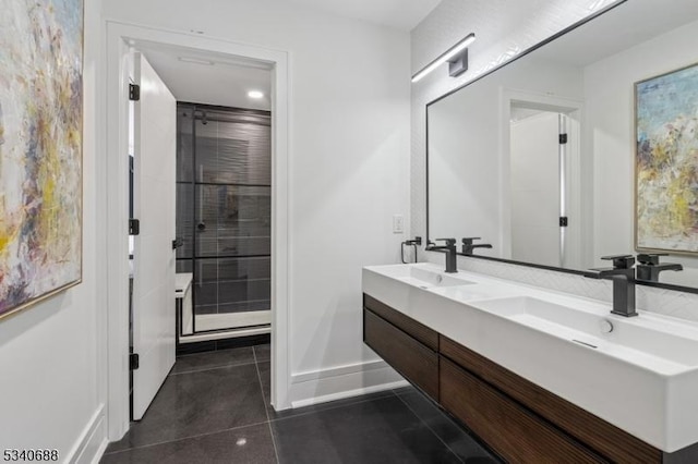 bathroom featuring double vanity, a sink, a shower stall, baseboards, and tile patterned floors