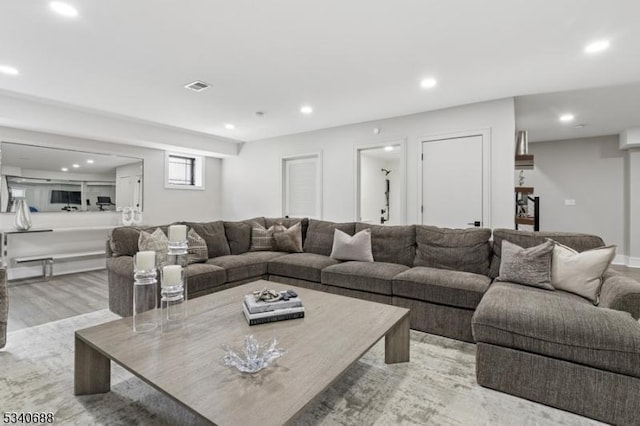 living room with light wood-type flooring, visible vents, and recessed lighting