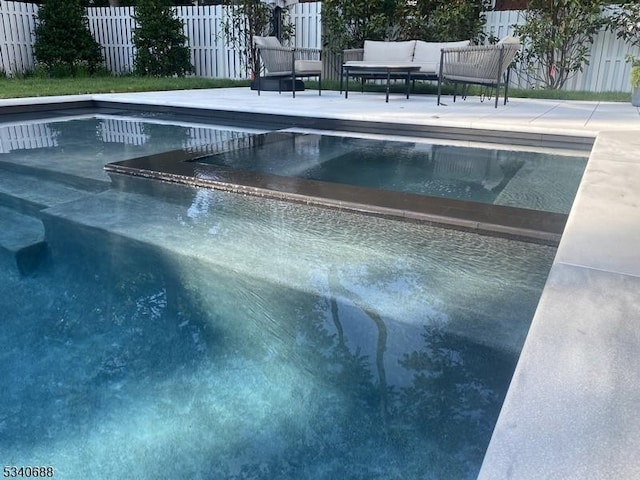 view of pool featuring a pool with connected hot tub, fence, and a patio