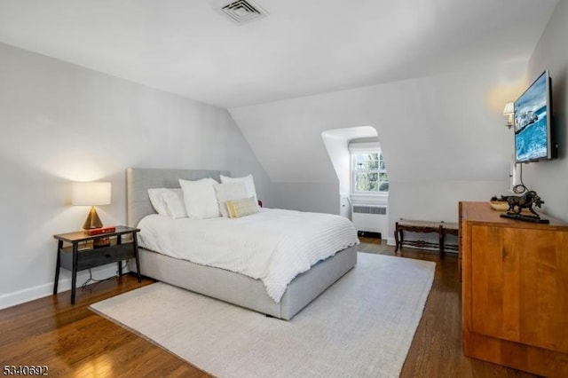 bedroom with lofted ceiling, wood finished floors, visible vents, and radiator