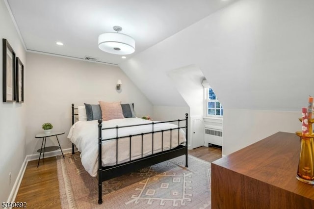 bedroom featuring lofted ceiling, radiator heating unit, baseboards, and wood finished floors