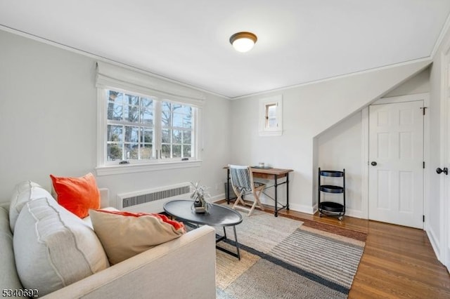 interior space with radiator, baseboards, wood finished floors, and ornamental molding