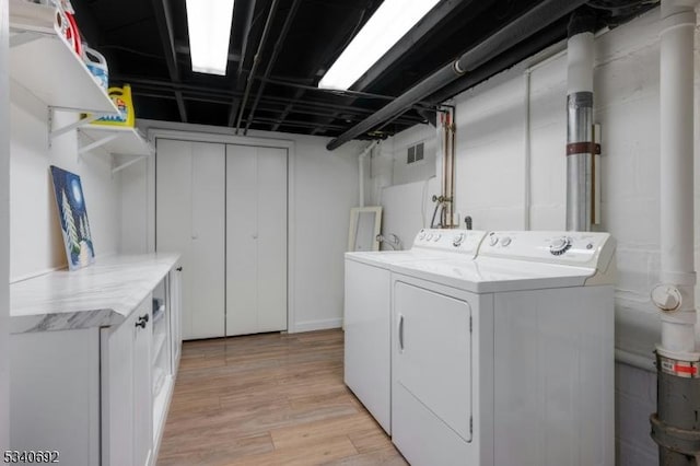 laundry area with visible vents, independent washer and dryer, and light wood finished floors