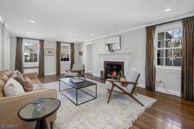 living room with a brick fireplace, baseboards, ornamental molding, and wood finished floors