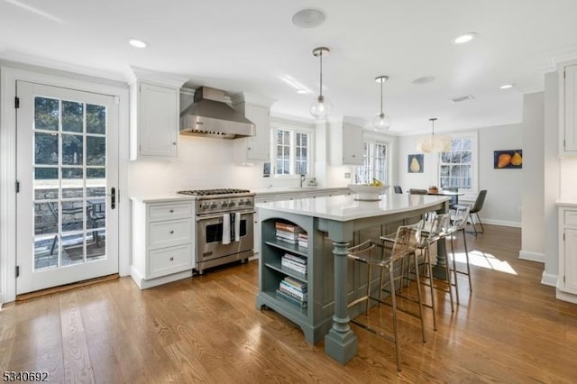 kitchen with white cabinetry, light countertops, wall chimney range hood, and high end stainless steel range