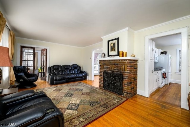 living room featuring baseboards, a fireplace, wood finished floors, and crown molding