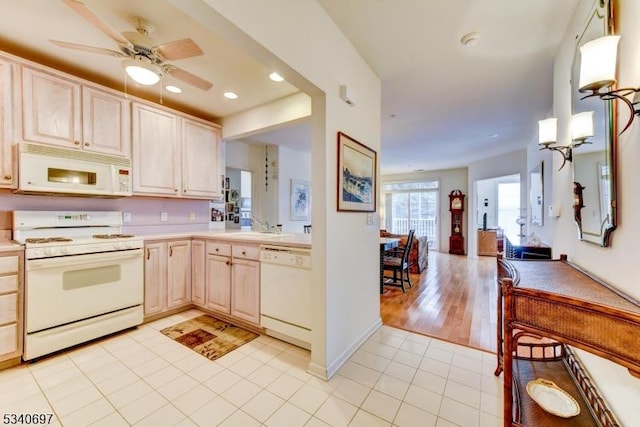 kitchen with light tile patterned floors, recessed lighting, light countertops, light brown cabinetry, and white appliances