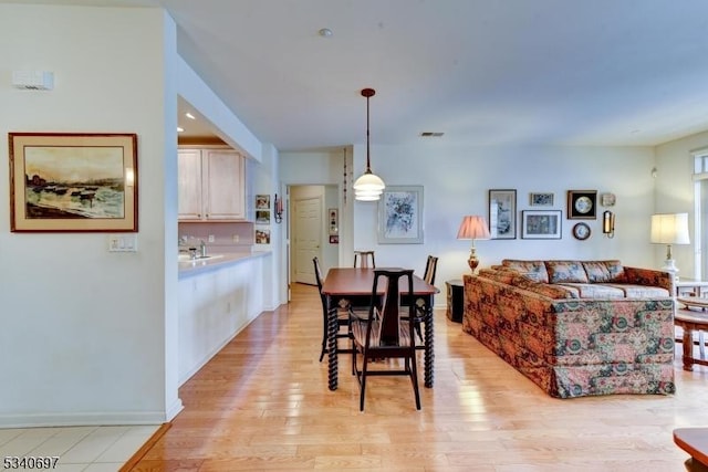 dining area featuring baseboards, visible vents, and light wood finished floors