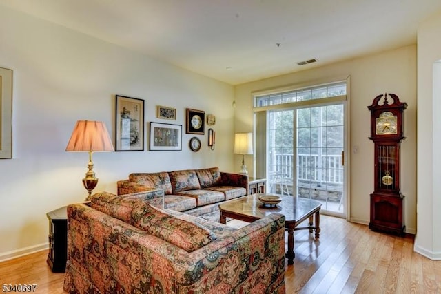 living area with light wood-style flooring, visible vents, and baseboards