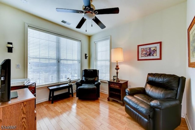 sitting room with a ceiling fan, light wood-type flooring, visible vents, and baseboards