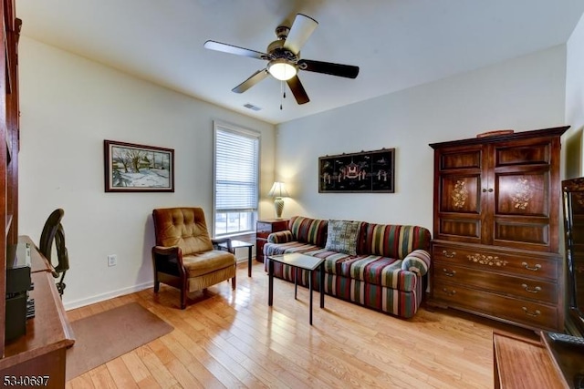 living area with baseboards, light wood-style flooring, visible vents, and a ceiling fan