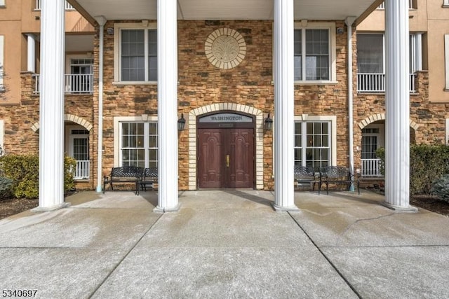 doorway to property with stone siding and a porch