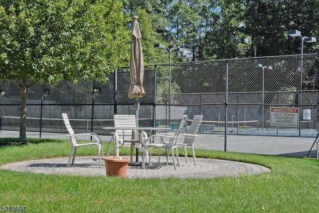 view of community with a tennis court and fence