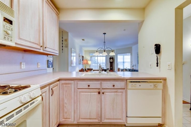 kitchen with light brown cabinetry, white appliances, and a sink