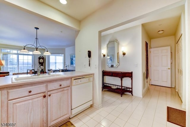 kitchen featuring pendant lighting, light countertops, light brown cabinets, white dishwasher, and a sink