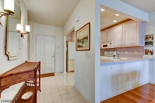 kitchen featuring recessed lighting, light countertops, a sink, white appliances, and baseboards