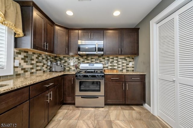 kitchen with tasteful backsplash, recessed lighting, appliances with stainless steel finishes, dark brown cabinetry, and light stone countertops