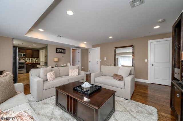 living area with baseboards, light wood-style flooring, visible vents, and recessed lighting