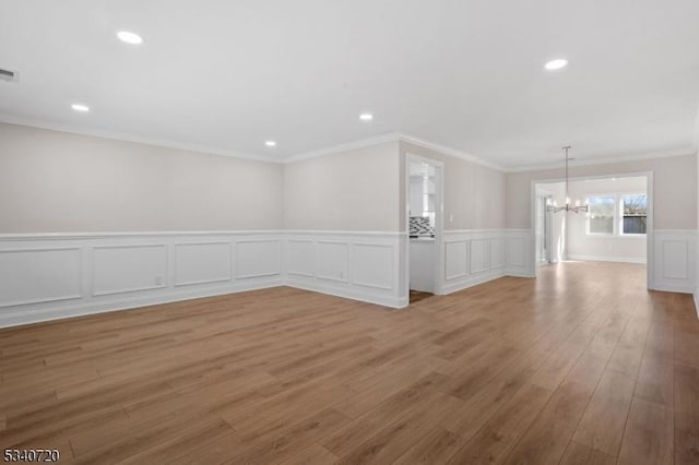 unfurnished room with light wood-style floors, recessed lighting, a chandelier, and crown molding