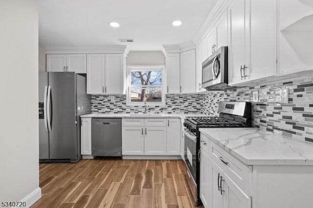 kitchen with stainless steel appliances, a sink, visible vents, light wood-style floors, and white cabinetry