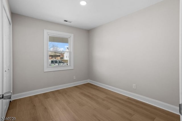 empty room with baseboards, visible vents, and wood finished floors