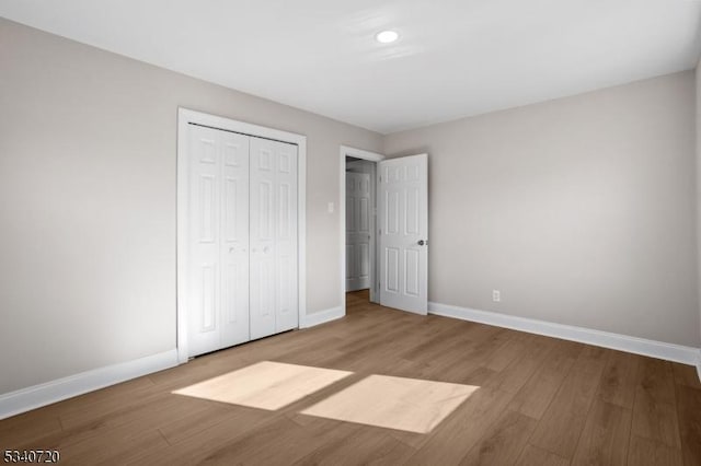 unfurnished bedroom with a closet, baseboards, and wood finished floors