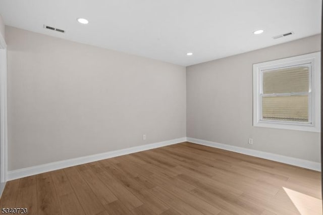 spare room with light wood-type flooring, baseboards, visible vents, and recessed lighting