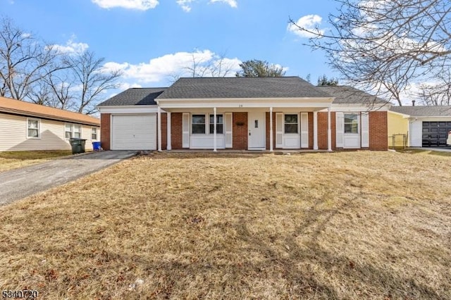 ranch-style house featuring driveway, a garage, brick siding, covered porch, and a front yard