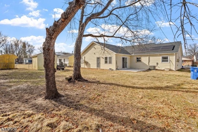 back of house with a patio, a yard, cooling unit, and roof mounted solar panels