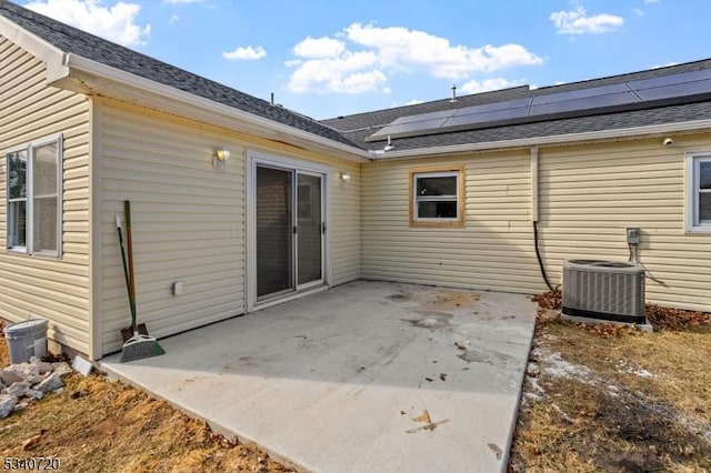 back of property with solar panels, a patio, and central AC unit