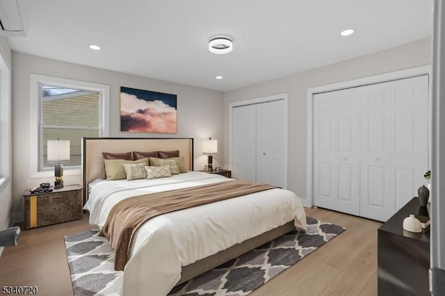 bedroom featuring recessed lighting, light wood-style flooring, and multiple closets