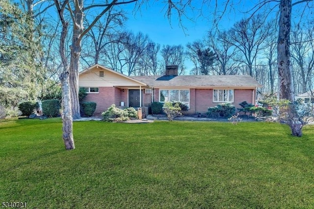 ranch-style home featuring a chimney, a front lawn, and brick siding