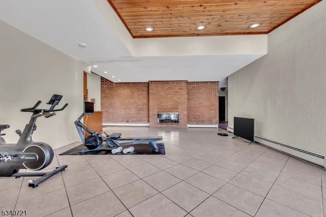 workout area with light tile patterned floors, wooden ceiling, brick wall, baseboard heating, and a brick fireplace