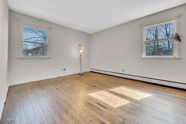 spare room with a baseboard radiator, baseboards, and hardwood / wood-style floors