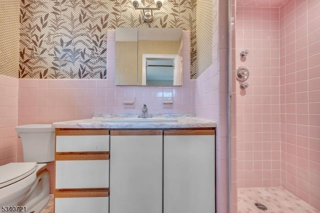 full bath with toilet, vanity, a shower stall, and tile walls