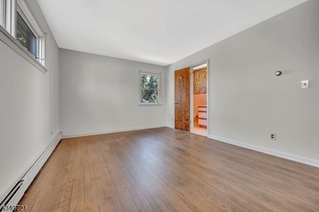 spare room with a baseboard heating unit, baseboards, and wood finished floors