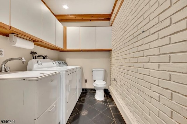 bathroom with washer and dryer, tile patterned flooring, toilet, and brick wall