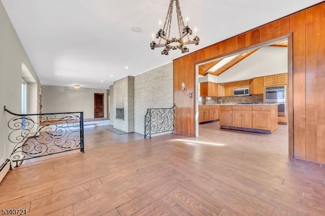 interior space featuring lofted ceiling, a fireplace, light wood-style floors, stairway, and an inviting chandelier