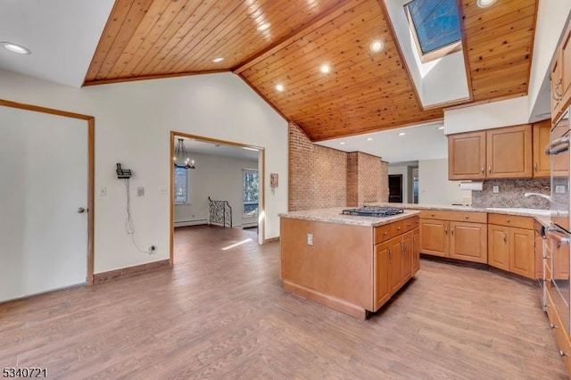 kitchen with a skylight, light wood finished floors, a baseboard radiator, wood ceiling, and a kitchen island