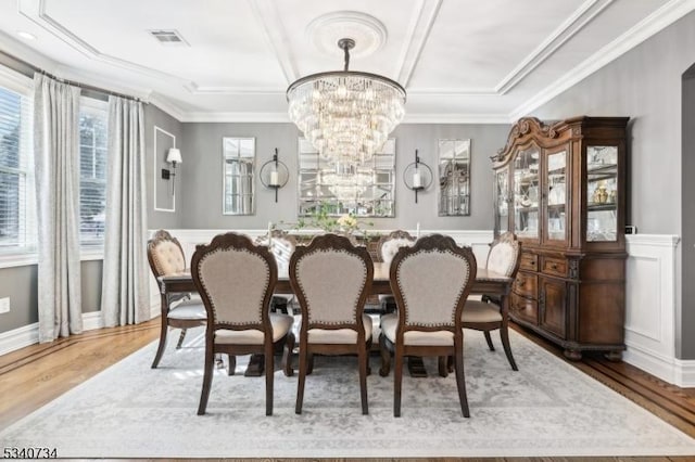 dining area featuring ornamental molding, wood finished floors, visible vents, and an inviting chandelier