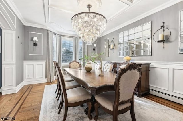 dining room featuring a wainscoted wall, light wood-style flooring, ornamental molding, a decorative wall, and a notable chandelier