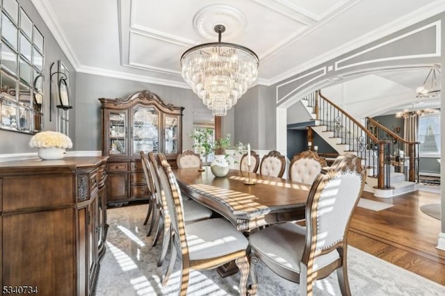 dining room featuring ornamental molding, arched walkways, a notable chandelier, and stairs