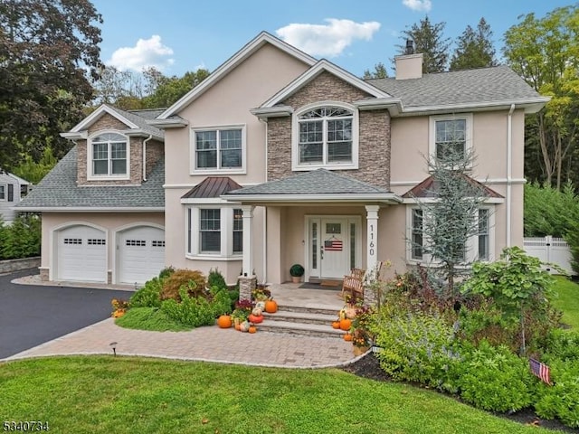 traditional-style home with aphalt driveway, a shingled roof, fence, and stucco siding