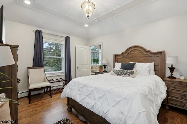 bedroom with a baseboard heating unit, a tray ceiling, wood finished floors, and recessed lighting