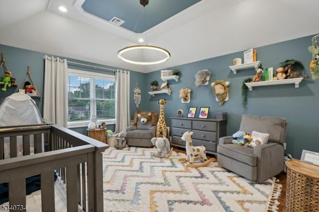 bedroom featuring a nursery area, a raised ceiling, visible vents, and recessed lighting