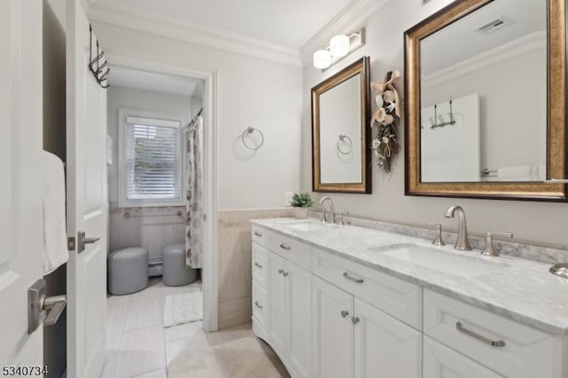 full bathroom featuring double vanity, crown molding, a sink, and wainscoting