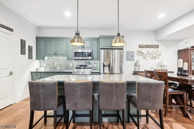 kitchen with stainless steel appliances, tasteful backsplash, a kitchen bar, and decorative light fixtures