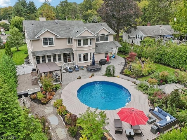 rear view of house featuring outdoor dining area, a patio, a chimney, outdoor lounge area, and driveway